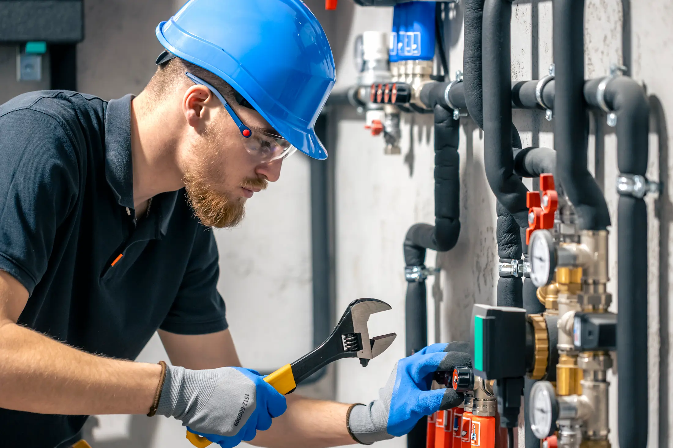 man installs heating system house checks pipes withwrench